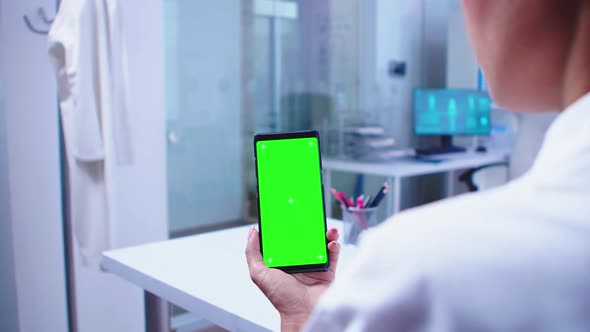 Medical Physician Looking at Phone with Green Screen alt
