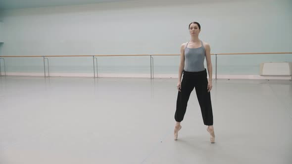 A ballerina stretches her legs in the rehearsal room. Ballet rehearsal.