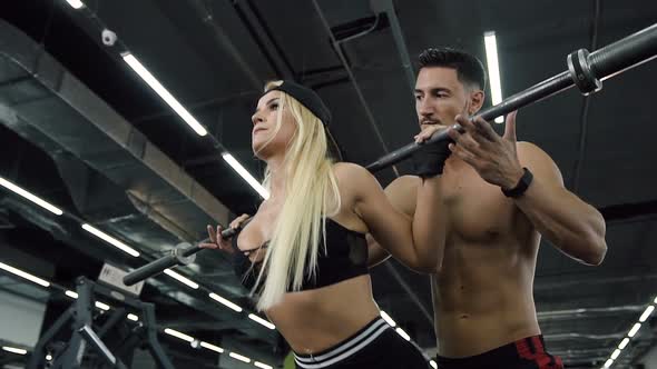 Concentrate Sport Woman Squating with Barabells During Personal Training in the Gym. alt