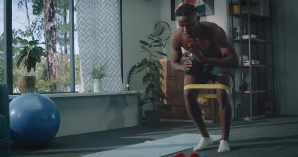 African American Male Doing Physical Exercise with Elastic Bands at Home