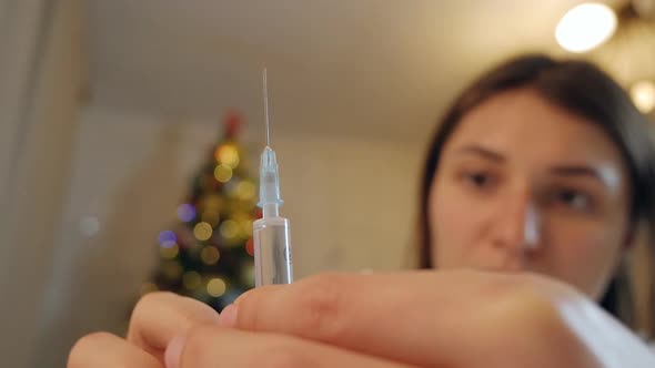 A Young Woman at Home Prepares a Prefilled Syringe for Injection By Tapping on the Syringe Ejecting