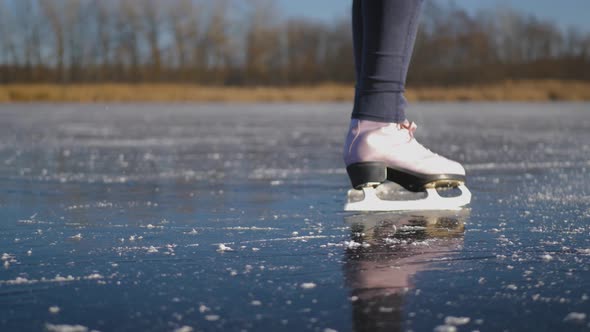 Young Woman Ice Skating on a Frozen Lake on a Freezing Winter Day. Legs of Skater on Winter Ice Rink alt