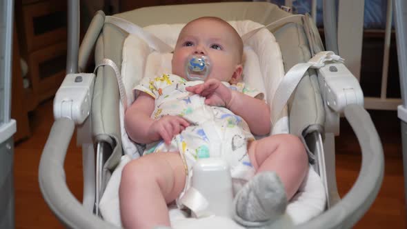 Baby Swings in an Electronic Swing Cute Little Baby Boy Lying in Electric Rocking Chair