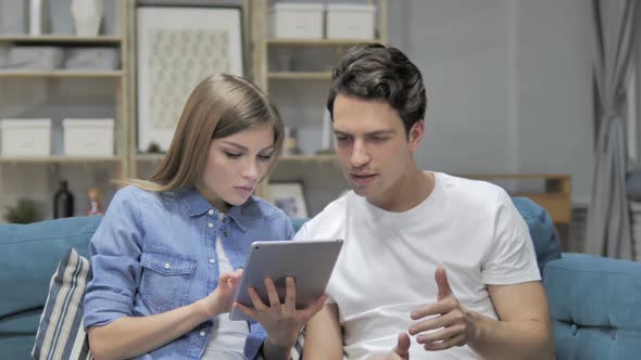 Happy Young Couple Celebrating Success While Using Tablet alt