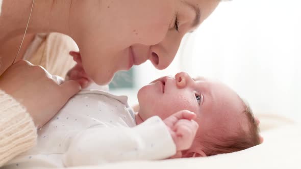 Closeup Shot of Beautiful Young Mother Cuddling and Stroking Her Little Baby Son Lying on Bed in Sun alt