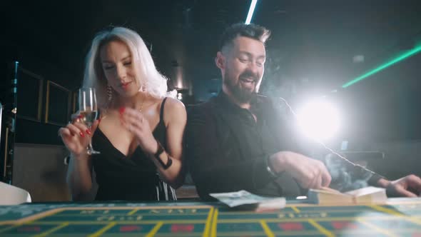 Bearded Man with Money in a Casino. Rich Businessman in Suit Is Flirting with a Beautiful Woman. alt