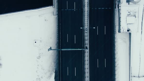 Aerial View Vertically Down the Road Bridge in Winter in Snowfall Over the Bay alt