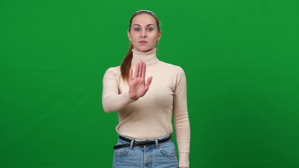 Young Woman Stretching Hand at Camera Showing Stop Gesture and Shaking Head No alt