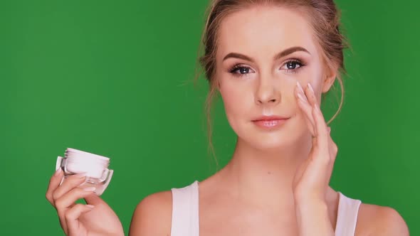 Woman Applying Cream Under Her Eye and Laughing alt