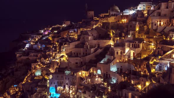 Beautiful timelapse view of Oia village on Santorini, Greece at night, tilt, pan, zoom in