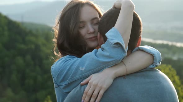 Slow Motion of a Young Woman Gently Hugs Her Boyfriend at Sunset. alt