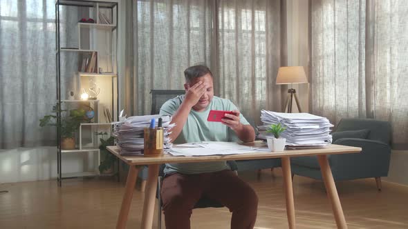 Fat Asian Man Being Upset Losing Game On Smartphone After Working With Documents At The Office alt