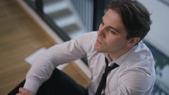 High Angle View Frustrated Man Holding Head in Hands Thinking Sitting on Office Floor alt