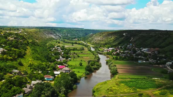 Aerial drone view of village in a valley in Moldova, multiple buildings, greenery, hills alt