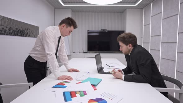 Side View of Two Thoughtful Professional Men Analyzing Graphs Planning Strategy in Office Indoors alt
