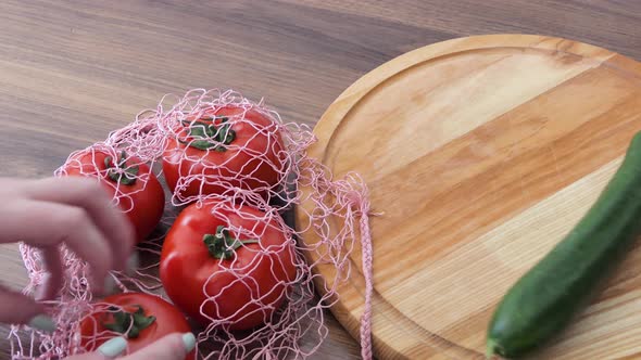 A Woman Takes Out Cucumber Tomatoes From a Reusable Grocery Bag Vegetables on a Table in the Kitchen alt