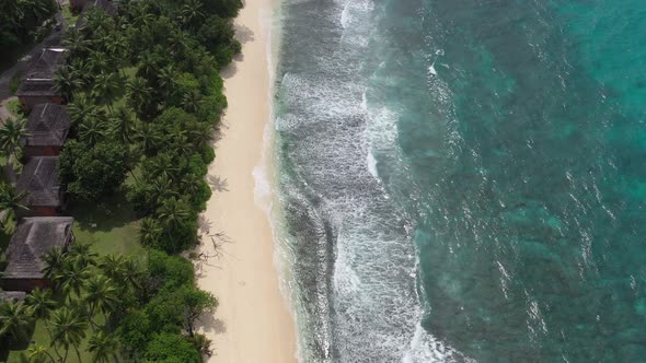 Aerial view of coastline chalets and forest meeting sea Praslin Seychelles