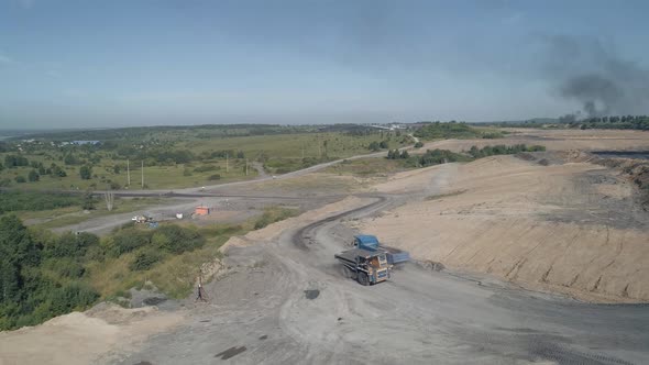 The Drone Flies Up to a Dirt Road Along Which Powerful Dump Trucks Ply and Easily Overcome Difficult