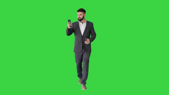 Businessman Walking and Making a Video Call on a Green Screen, Chroma Key. alt