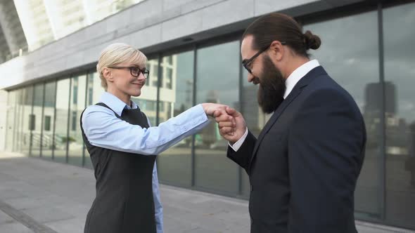 Business Man Bending to Kiss Female Partners Hand, Woman Displeased With Sexism