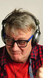 Expressive Adult Senior Man Listens to Music on His Headphones Sings Along and Moves alt
