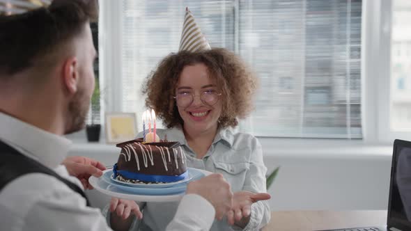 Birthday Online Smiling Girlfriend with Festive Cap on Head Makes Wish and Blows Out Candles on Cake alt