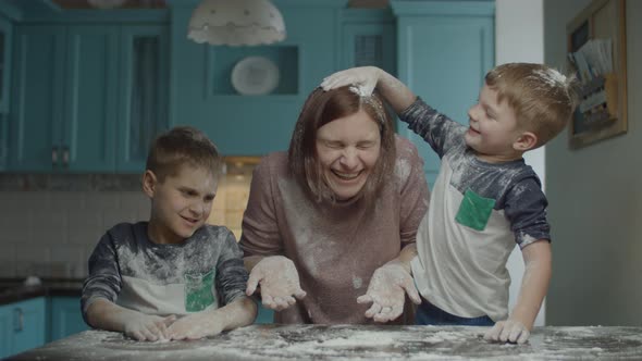 Happy family of mother and two kids having fun with flour while cooking cookies.  alt