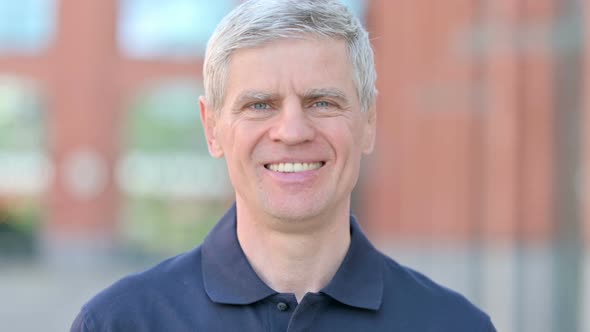 Outdoor Portrait of Cheerful Middle Aged Man Smiling at Camera alt