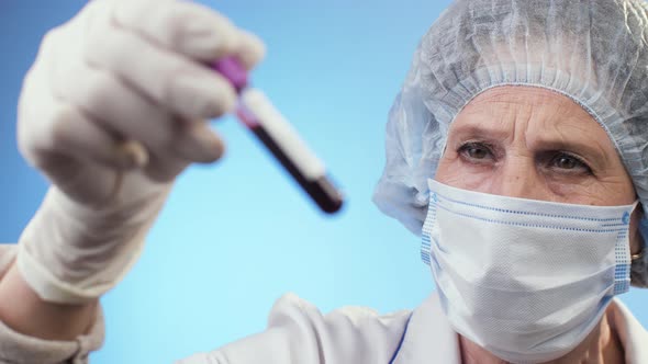 Doctor Analysing a Blood Tube with Covid-19 Positive Result alt