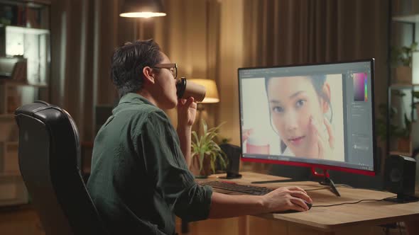 Male Digital Editor Drinking Coffee While Works In Photo Editing Software On His Personal Computer alt
