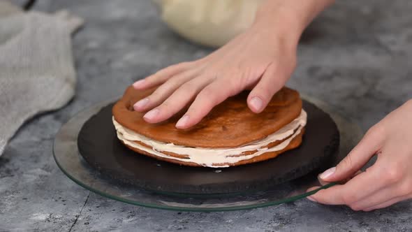 Baker Pastry Chef Smoothies a Layer of Caramel Cream on a Cake Layer with a Spatula