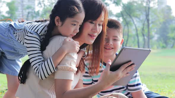 Mother using a digital tablet with her son and daughter, Happy family in park at weekend