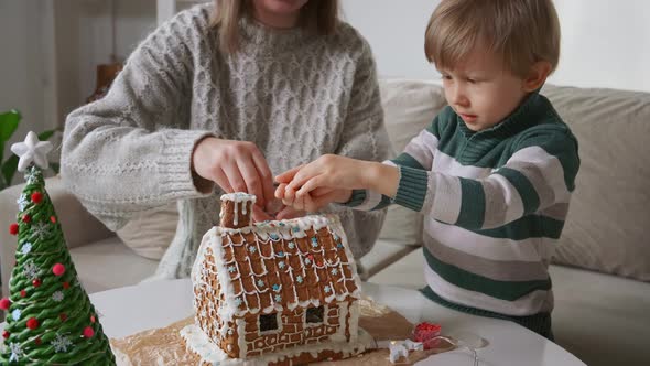Little Boy with Mother Decorating Christmas Gingerbread House Together Family Activities and alt