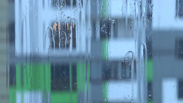 Streams of water and raindrops on the window glass in heavy rain, background