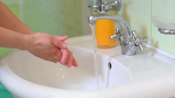 Woman washing her hands with soap in the bathroom.