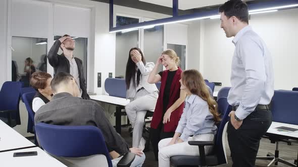 Joyful Caucasian Woman Talking to Group of Cheerful Colleagues in Office Laughing alt
