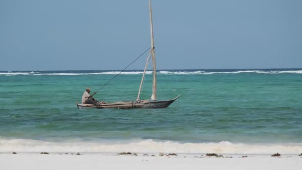 African Fisherman on an Old Dry Wooden Boat Sail in Ocean at High Tide Zanzibar alt