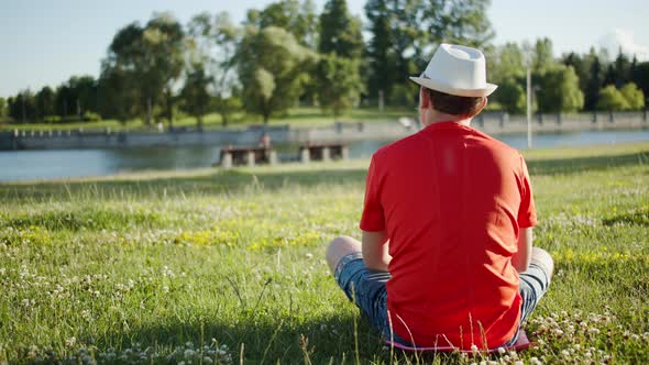 Man in a hat sits in nature on a sunny day, summer time, copy space alt