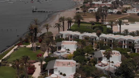 Smooth Aerial Shot of Luxury Embankment Greenery Palms Pools Coastline Hotel