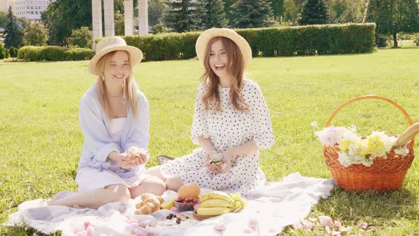 Two young beautiful hipster woman in trendy summer sundress and hats posing outdoors