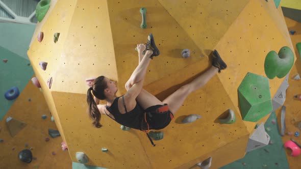 Sportswoman Climber Moving Up on Steep Rock Climbing on Artificial Wall Indoors