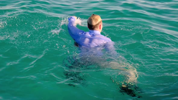 A Funny Man in a Shirt Tie and Socks Swims in the Sea on a Sunny Day Then Dives Under the Water alt