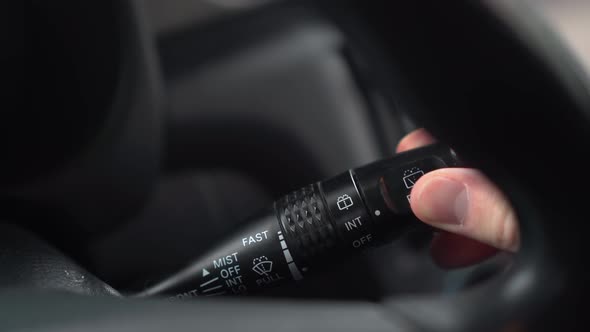 A Man Turns on the Wipers By Turning the Lever in the Car alt