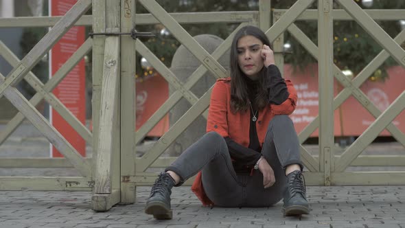 depressed lonely pretty young woman sitting on ground in the city alt