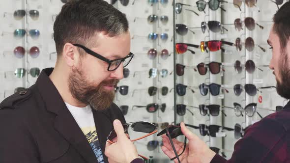 Professional Optometrist Showing Glasses for Sale To His Male Customer alt