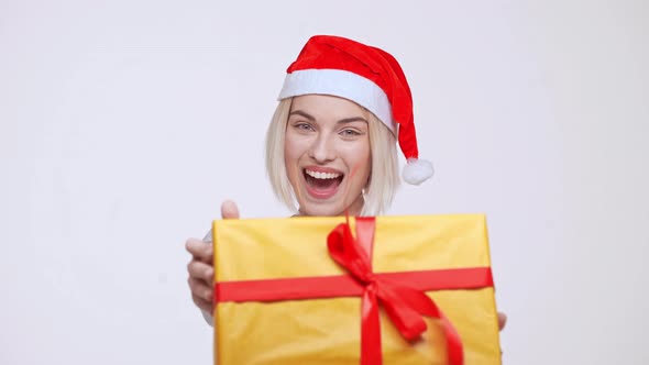Best Moment of Holidays Yooung Pretty Blonde Girl in Christmas Hat Giving Big Yellow Gift Box White alt