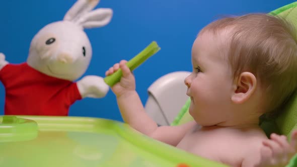 Cute baby girl eating celery and playing