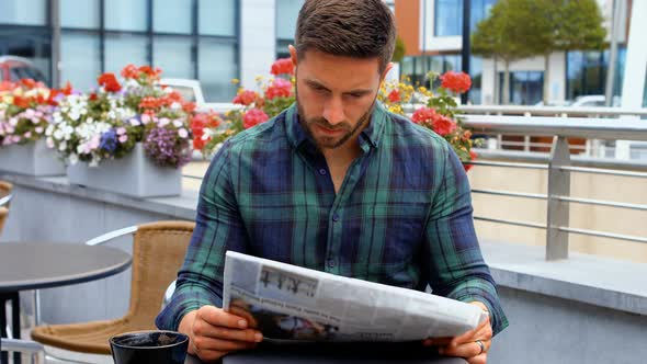 Businessman reading newspaper while having coffee alt