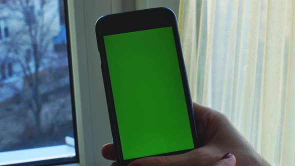 Caucasian Female Hands Holding Black Smartphone with Green Screen
