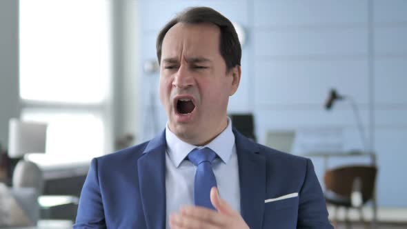 Portrait of Tired Businessman Yawning in Office alt